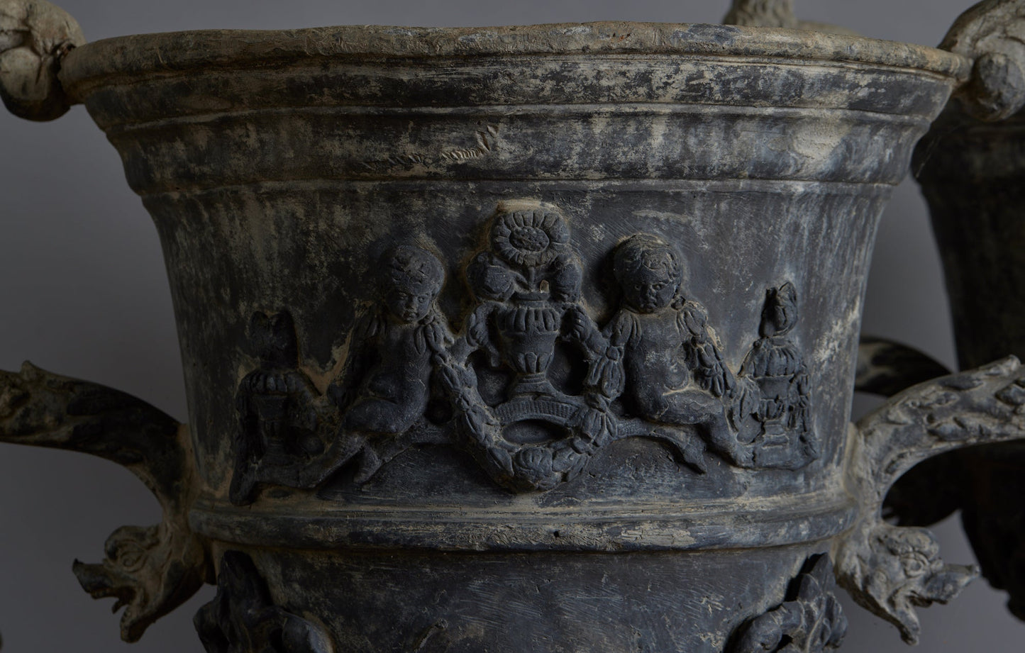 Set of Four English Late 19th Century Cast Lead Urns with Griffin Handles and Cast Applied Puttis in a Challased Form